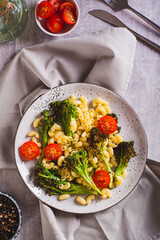 Salad of pasta, tomatoes and fried broccoli sprouts on a plate on the table top and vertical view
