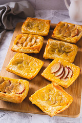 Small upside-down puff pastry cakes with banana and apple on a board vertical view