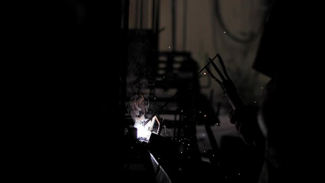 Welder working on a construction site. Welding process on a dark background.