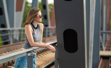 The girl stands on the railway bridge