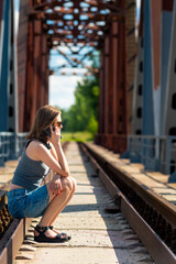 Young woman with phone sitting on rails