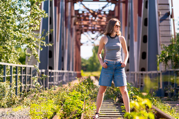 A young woman stands alone on a bridge