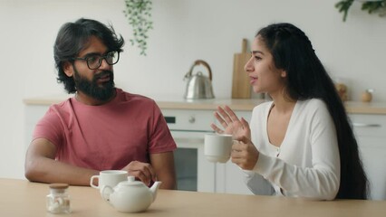 Two friends woman and man talking in kitchen girl talk to arabian guy tell funny joke laugh multiethnic diverse couple laughing discussing news communicate drinking tea coffee on meeting date at home - Powered by Adobe