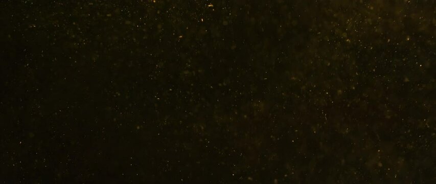 Blurred bokeh background of gold dust particles slowly floating in the air