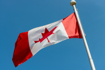 canadian flag waving against blue sky