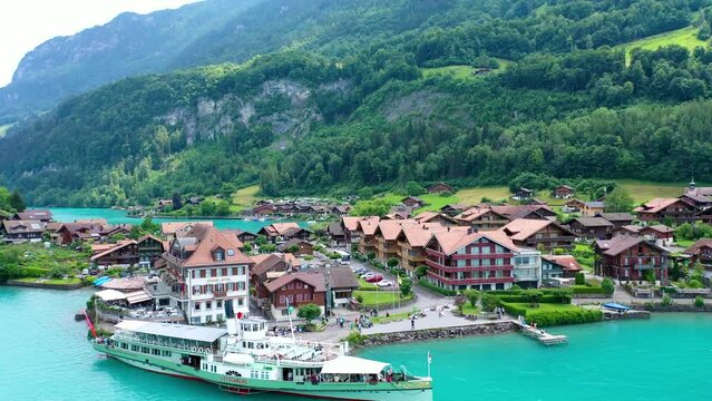 A village in switzerland with a tourist ship anchored in the port