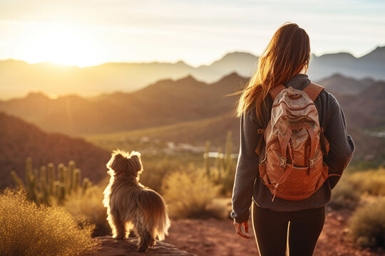 Behind view of a young healthy caucasian woman walking her mixed breed dog on a trail in the mountains of Phoenix, Arizona