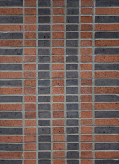 two tone brick wall in terra cotta and black in stack bond pattern with four vertical rows of half-bricks in the center and a vertical row of stretchers in alternating orange and black color