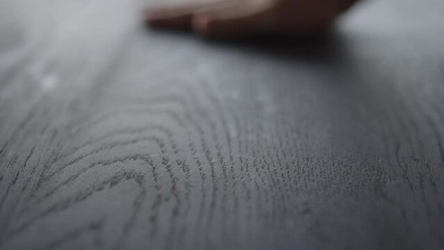 Slow motion man hand touches black oak table surface