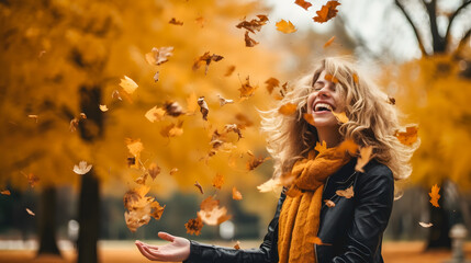 Une femme en train de jeter des feuilles en automne. - obrazy, fototapety, plakaty