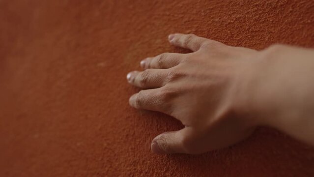 Slow motion man hand touching terracotta wall