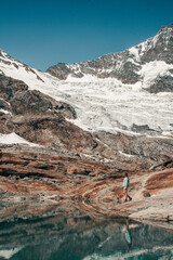 A young girl hiking along a scenic trail in Saas Valley, Swiss Alps and a majestic glacier in the background