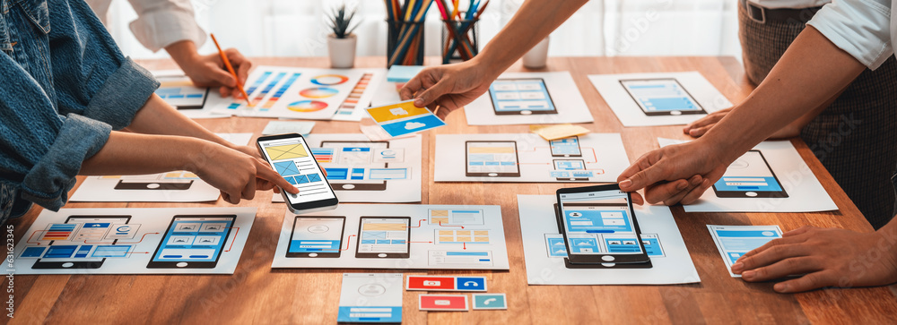Poster Panorama shot of front-end developer team brainstorming UI and UX designs for mobile app on paper wireframe interface. User interface development team planning for user-friendly UI design. Scrutinize