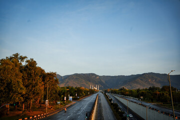 Obraz premium Faisal Masjid in winters, with the Margalla Hills in the background. Clear sky and green trees enhance the serene scene.