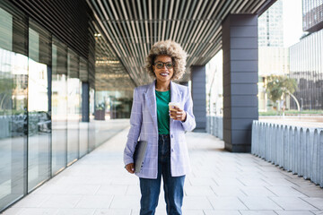 Portrait of Young African American business woman in trendy blazer and eyeglasses standing on...
