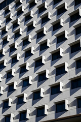 Vertical image of a facade of a modern multi-storey residential building wall with symmetrical windows