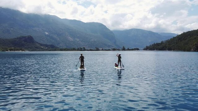 Summer Vacation with Paddle Board. Sup Board Journey. Two girls with children enjoing watersport on beautiful Aegean Sea landscape