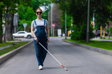 Naklejka premium Blind pregnant woman walking down the street with a cane. 