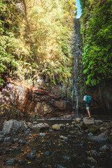 Male toursit with backpack enjoys exploring green overgrown waterfall. 25 Fontes waterfalls, Madeira Island, Portugal, Europe.