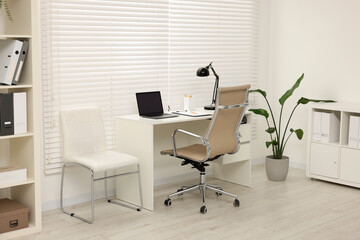 Doctor's workplace. Chairs, laptop and clipboard on white table in clinic