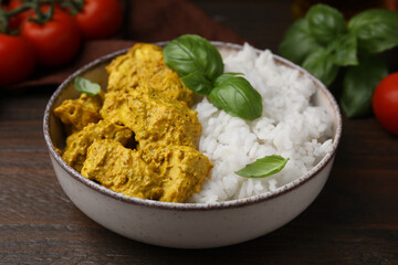 Delicious rice and chicken with curry sauce on wooden table, closeup