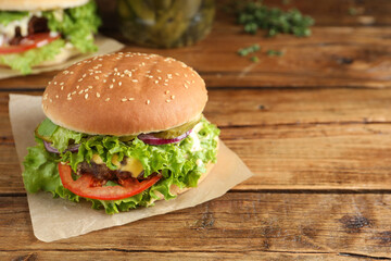 Delicious burger with beef patty on wooden table, space for text