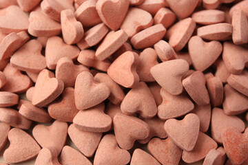 Heart shaped vitamins for pets as background, closeup