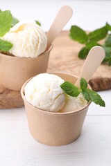 Delicious vanilla ice cream and mint on white wooden table