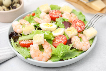 Delicious Caesar salad with shrimps on light table, closeup