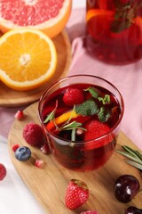 Glass of delicious sangria, fruits and berries on table