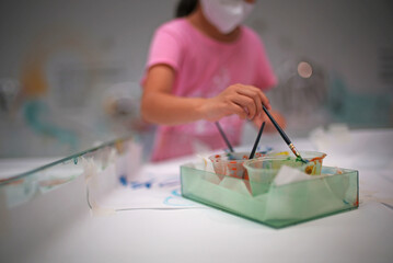 a little girl draws a picture using paint brushes
