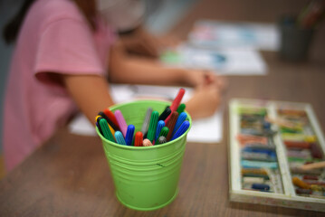 girl drawing with a pencil on the table in the background. focus on drawing instruments