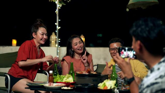 4K Diversity Asian people friends using mobile phone taking picture or video call online live streaming on social network during celebration dinner party at home outdoor rooftop on holiday vacation.
