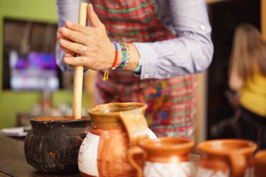 Tourist making hot chocolate in a clay pot with a traditional molinillo whisk in Guatemala