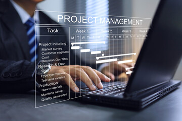 Project manager working on laptop in office to updating tasks and milestones progress planning with Gantt chart scheduling interface  on virtual screen to co working another member in own team.