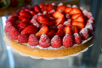 French fresh baked sweet pastry with fresh red summer fruits and berries in confectionery shop close up
