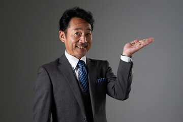 右側を手のひらで指すミドルエイジのビジネスマン　黒背景