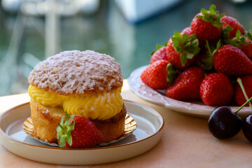 Tarte tropezienne or La Tarte de Saint-Tropez - dessert pastry consisting of filled brioche with cream and fresh berries served outdoor with fresh ripe strawberry