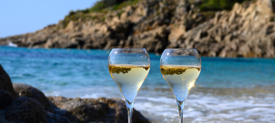 Summer time in Provence, two glasses of cold champagne cremant sparkling wine on sandy beach near...