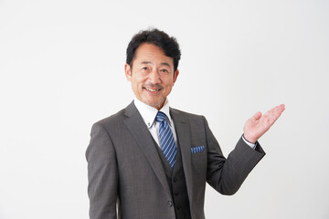 右側を手のひらで指すミドルエイジのビジネスマン　白背景