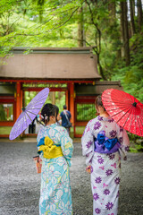 Back view of two women wearing Japanese yukata summer kimono and holding Japanese traditional oil...
