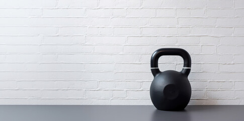 Black kettlebell in the gym with brick wall background