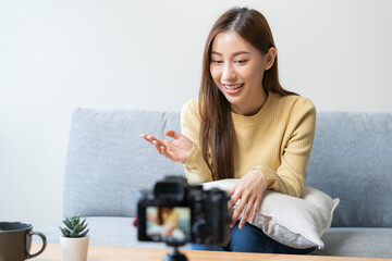 Vlogger influencer, attractive asian young woman blogger, content maker looking at camera, recording interview sit on sofa, talk on video shooting social media, live broadcast with technology at home.