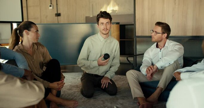 A man in a shirt gives his opinion at a group therapy for people in the office