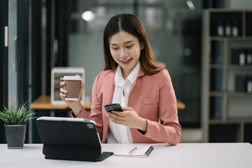 woman sits in a office working on smartphone play social media and enjoys a coffee.