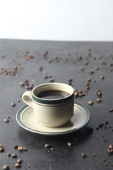 Coffee cup and coffee beans on a black stone background.