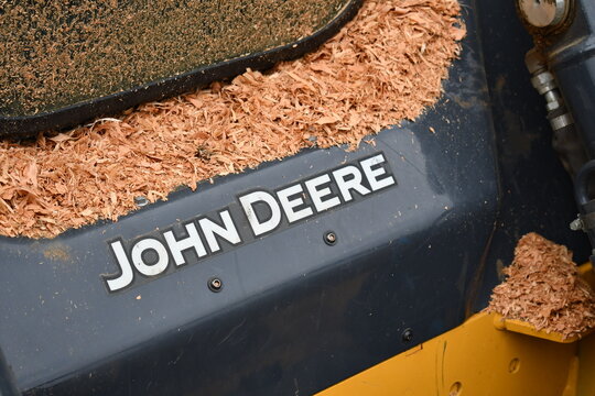 John Deere skid-steer covered in bark dust.