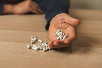 Stressed, sad asian young man, male take medicine, lying on table. Close up hand of abuse overdose...