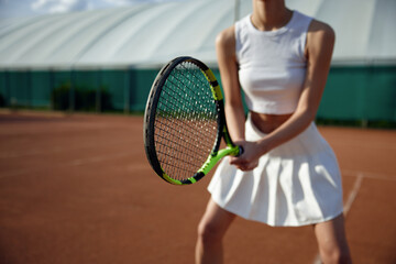 Closeup view on female tennis player holding racket
