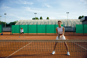 Woman and man behind net playing tennis double set game